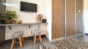 Una cocina moderna con un televisor de pantalla plana, un ventilador y dos taburetes.