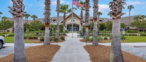A pathway leading to a building with an American flag, surrounded by palm trees and a wheelchair-accessible sign.