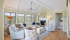 A spacious living room with a high ceiling, large windows, a fireplace, and a view of the outdoors. - Seabrook Villa with Loft & Views! Walk to Beach! Pool! (Seabrook Island)