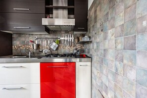 A modern kitchen with a gas stove, stainless steel appliances, and a red accent cabinet.