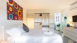 Ett modernt hotellrum med en stor säng, en garderob, ett skrivbord och en TV.