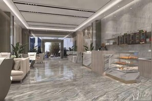 A modern hotel lobby with marble flooring, a reception desk, seating area, and a glass display case with pastries. - Meidi Hotel (Shenzhen Bao'an Airport Pingluanshan Metro Station Branch) (Shenzhen)
