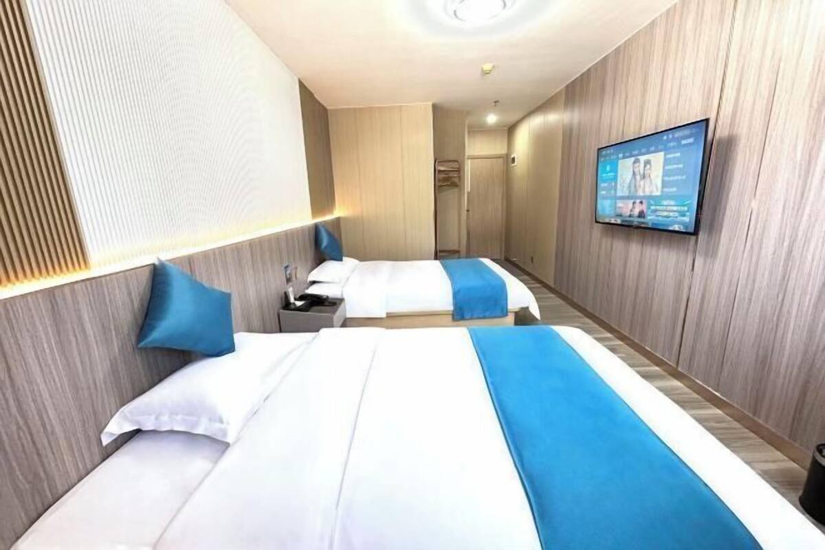 A hotel room with two beds, a TV, and a wooden wall.