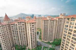 Um complexo de edifícios residenciais altos, com vários prédios de apartamentos, uma via central e áreas verdes ao redor.