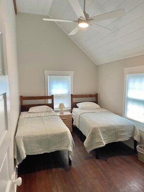 A bedroom with two single beds, a ceiling fan, and a window with blinds. - Virginia Avenue 25 (Rehoboth Beach)