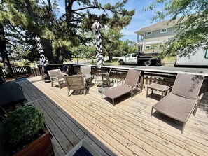 A wooden deck with outdoor furniture, a truck, and a building in the background. - Bayard Avenue 1600 (Dewey Beach)