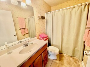 Bathroom features a sink, mirror, toilet, shower curtain, and towel rack.