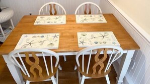A dining table with four white chairs, each with a unique wooden backrest design.