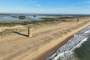 Une plage de sable avec une tour et des traces de pneus.