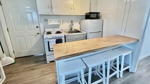A compact kitchen with white cabinetry, a wooden countertop, and a built-in microwave. - Christian Street 26 #1 (Rehoboth Beach)