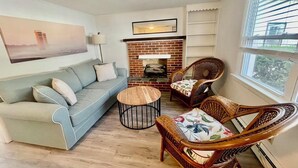 A living room with a sofa, two wicker chairs, a coffee table, a fireplace, and a large window. - Christian Street 26 #1 (Rehoboth Beach)
