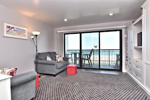 Relax in this stylish living area with a sofa, ottoman, and balcony overlooking the beach.