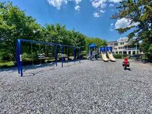 A playground with swings, slides, and a red fire hydrant. - Cedar Road 13 (Rehoboth Beach)