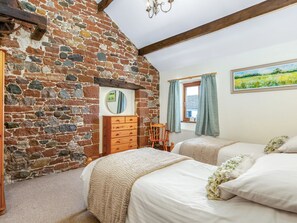A bedroom with a stone wall, wooden furniture, and a painting on the wall. - Barley Store - UK48910 (Allonby)