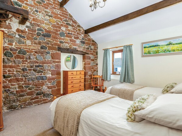 A bedroom with a stone wall, wooden furniture, and a painting on the wall.
