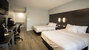 Une chambre d’hôtel avec deux lits simples, un bureau avec une chaise, une machine à café et un téléviseur.
