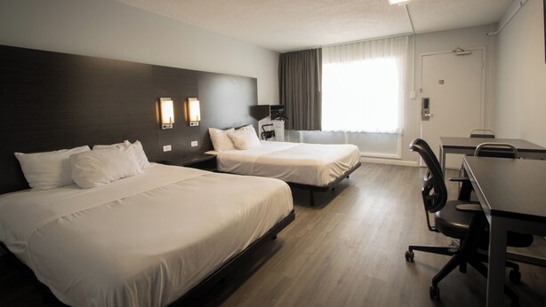 Une chambre d’hôtel avec deux lits, un bureau et une chaise.