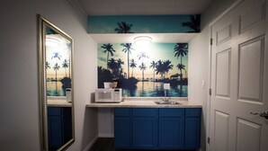 A compact kitchen with blue cabinets, a microwave, and a sink. - King Accessible Non-Smoking Pet Friendly (Henderson)