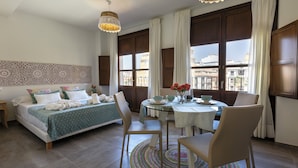Ein Schlafzimmer mit Bett, Nachttisch und Blick auf die Stadt durch große Fenster.