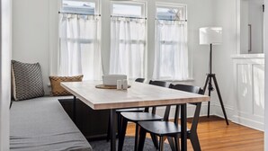 A dining area with a wooden table, black chairs, a bench with cushions, and a floor lamp. - Linden Hills Edina. Remolded Home Near the Lakes. King Bed. Sleeps 10. (Minneapolis)