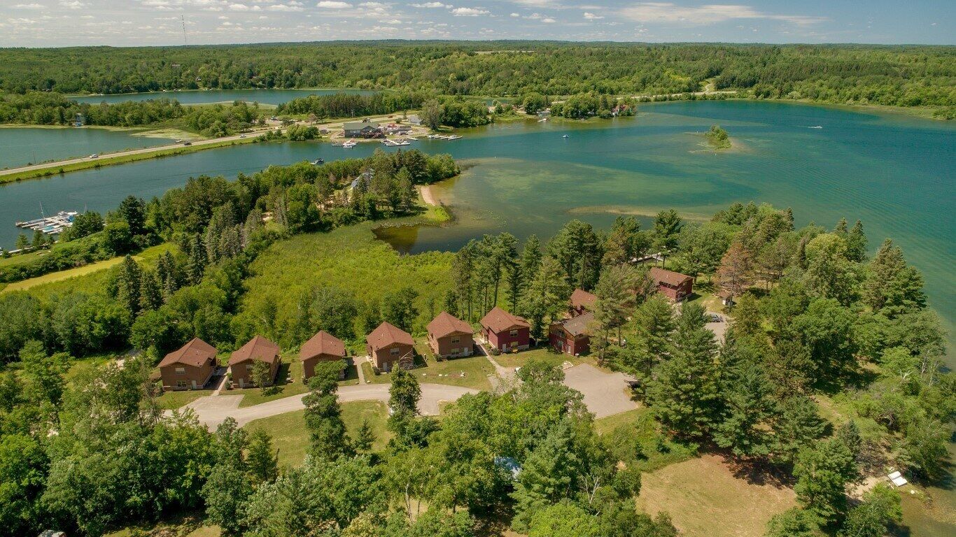An aerial view of a lakeside property with multiple cabins, a dock, and a clear view of the lake.