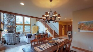 A spacious living area with a fireplace, a dining table, and a staircase leading to another level. - Zion Views- La Mesa Lodge + Resort Access (Orderville)