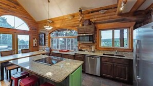 A spacious kitchen with a large island, wooden cabinetry, and a view of the outdoors. - Zion Views- The Ranch House +Resort Access (Orderville)