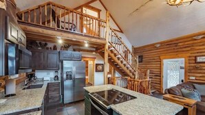 A spacious kitchen with granite countertops, stainless steel appliances, and a wooden staircase leading to a loft. - Zion Views- The Ranch House +Resort Access (Orderville)