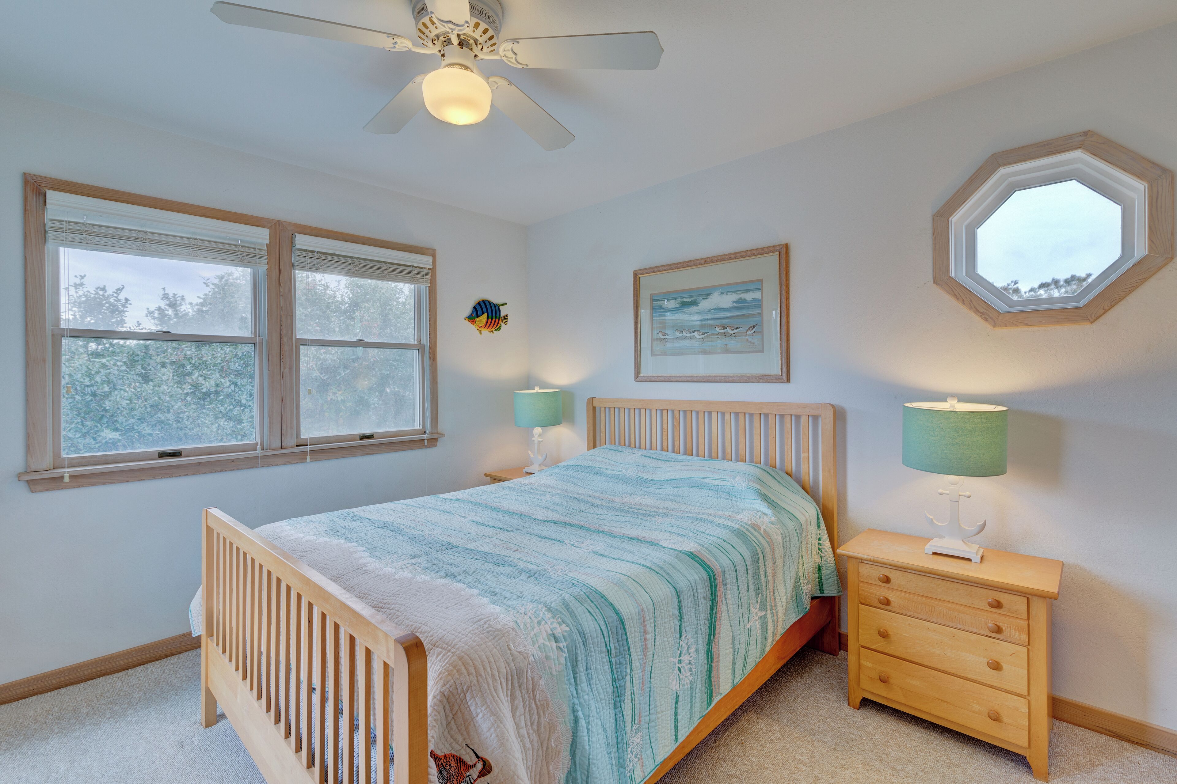 A bedroom with a bed, a nightstand, a lamp, a ceiling fan, and a window.
