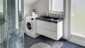 A modern bathroom with a washing machine, a sink, and a glass shower enclosure. - 3 bedroom nice home in Væggerløse (Væggerløse)