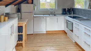A kitchen with white cabinets, a wooden countertop, a built-in dishwasher, a stove, and a window above the sink. - 3 bedroom nice home in Væggerløse (Væggerløse)