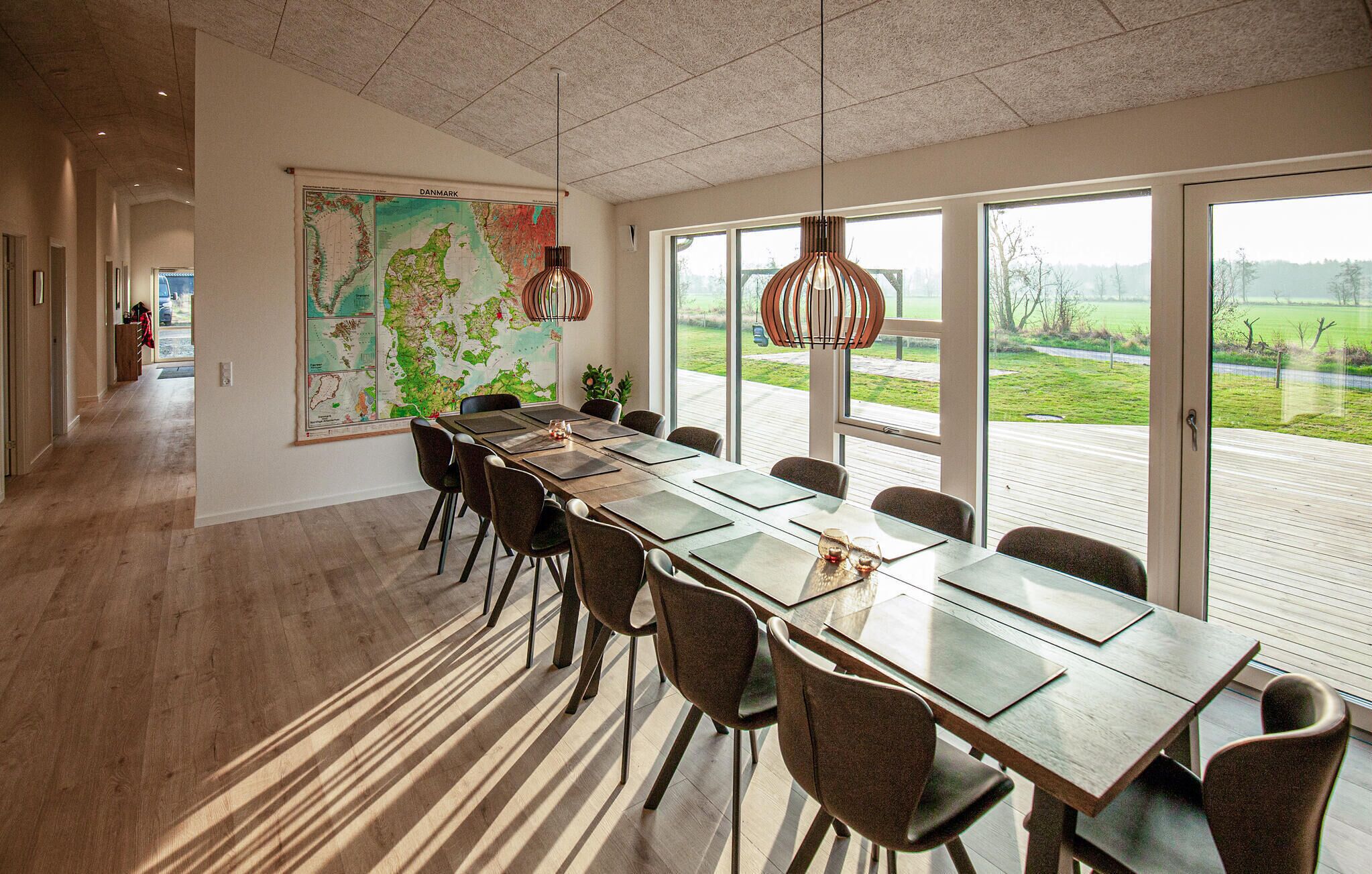Uma sala de conferência moderna com um mapa grande na parede, uma mesa comprida com cadeiras e amplas janelas que oferecem vista para o exterior.