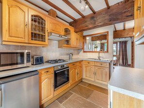 Una cucina con mobili in legno, un forno a microonde, un piano cottura e una lavastoviglie.