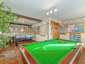Ein Billardtisch mit grüner Spielbahn, ein Tischfußballtisch und ein Billardgestellerücken.