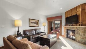 Una sala de estar con chimenea, un sofá, una mesa de centro y un televisor.