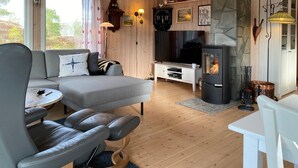 A cozy living room with a sofa, a leather chair, a TV, a fireplace, and wooden walls. - 2 bedroom amazing home in Agdenes (Agdenes)