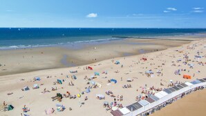 Une vaste plage dotée de nombreux transats et parasols, une rive sablonneuse et une vue dégagée sur l’océan.