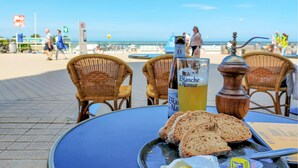 Une table avec une bouteille de Blanche de Narmer, des tranches de pain, un moulin à poivre et un verre de bière.