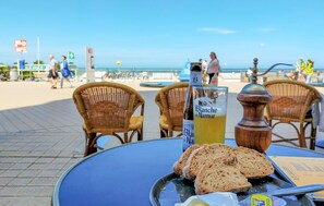 A table with a bottle of Blanche de Narmer, slices of bread, a pepper grinder, and a glass of beer. - Beach front apartment in Oostende (Oostende)