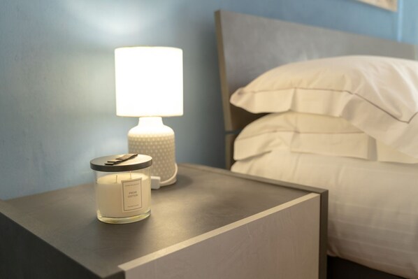 A bedside table with a lit candle and a container of fresh cotton.