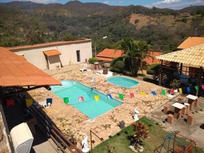 A rooftop pool area with two pools, surrounded by buildings and a mountainous landscape. - Pousada Só Alegria (Mario Campos)