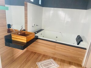 A modern bathroom with a wooden vanity, a glass bathtub, and a wooden floor. - Pousada Só Alegria (Mario Campos)