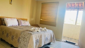 A bedroom with a bed, a window with blinds, and a view of the outside.