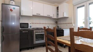 Una cocina moderna con armarios blancos, electrodomésticos de acero inoxidable y una mesa de comedor de madera.