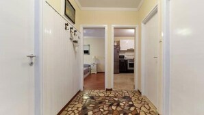 Un pasillo con piso de baldosas que conduce a un dormitorio y una zona de cocina.