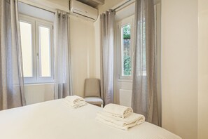 A hotel room with a bed, a chair, and a window with curtains.