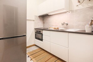 A modern kitchen with a stainless steel refrigerator, built-in oven, and a black countertop.
