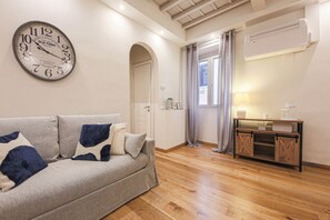 A living room with a sofa, a clock, a wooden cabinet, and a door.