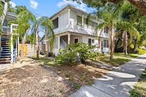 A two-story house with a porch, surrounded by trees and a gravel driveway. - Heart of the City Hideaway 1 bed, 1 bath (St. Petersburg)