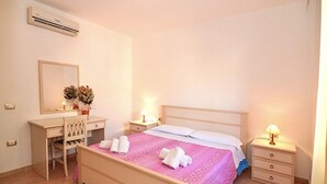 A bedroom with a bed, bedside tables, a desk, a chair, and a mirror.